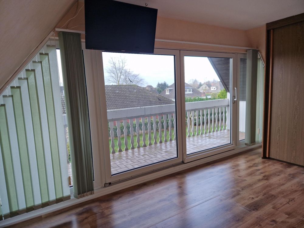 Zimmer mit großer Fensterfront und Zugang zum Balkon